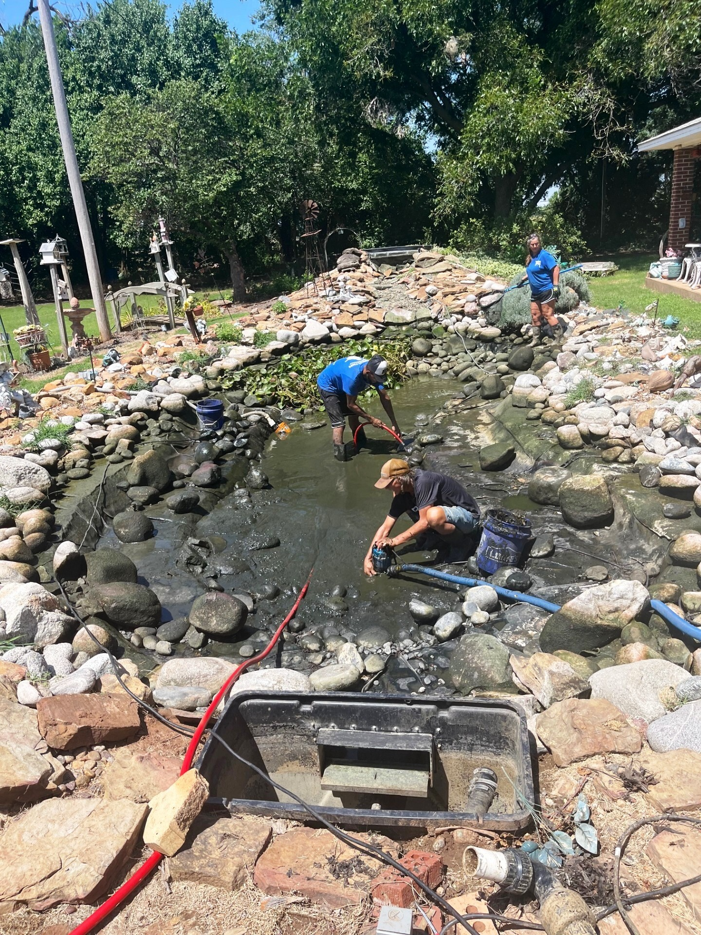 Specialist shaping pond basin and filtration layout with precise landscape construction tools