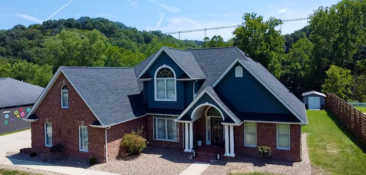 Roof Replacement in Charleston - WV in progress as workers install new shingles across a steep roof