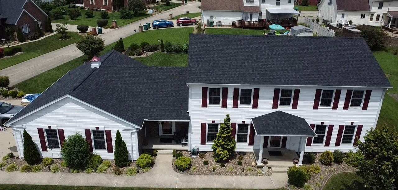 Crew completing roof replacement on a Charleston - WV home while aligning shingles along the ridge